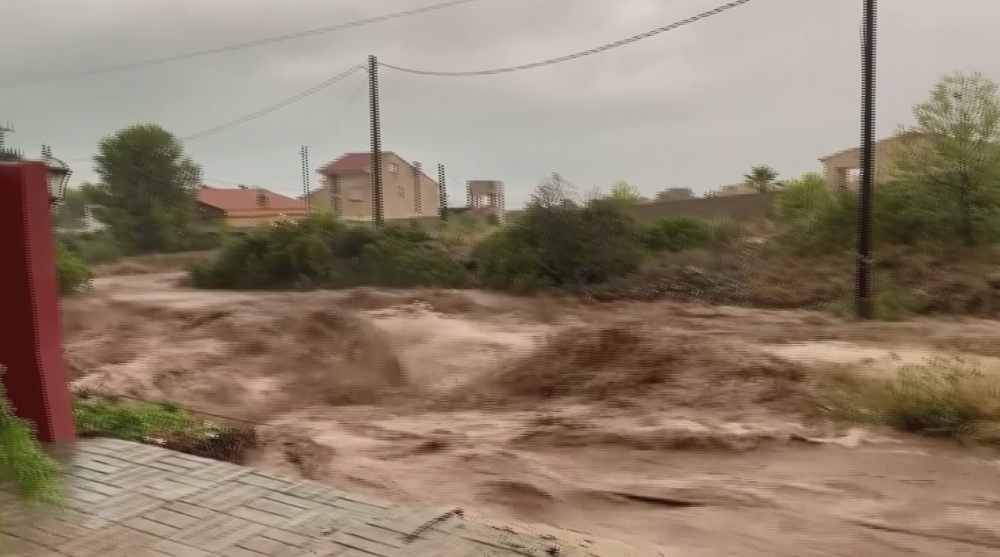 Torrents of flood water rush next to homes in Spain