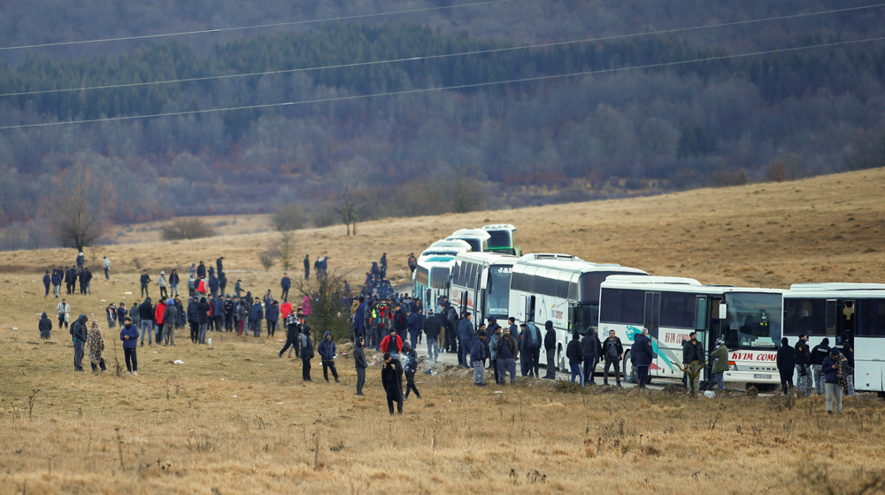Refugees wait in cold to be bussed from burnt Bosnia camp