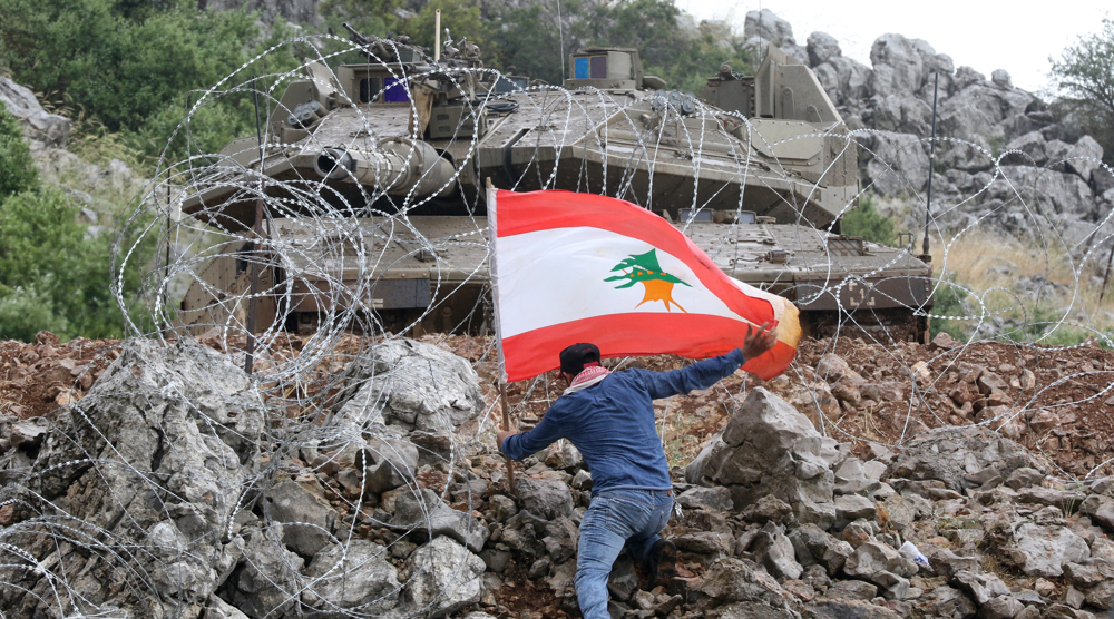 A Lebanese protester plants the national flag across the fence from an Israeli tank during an anti-I