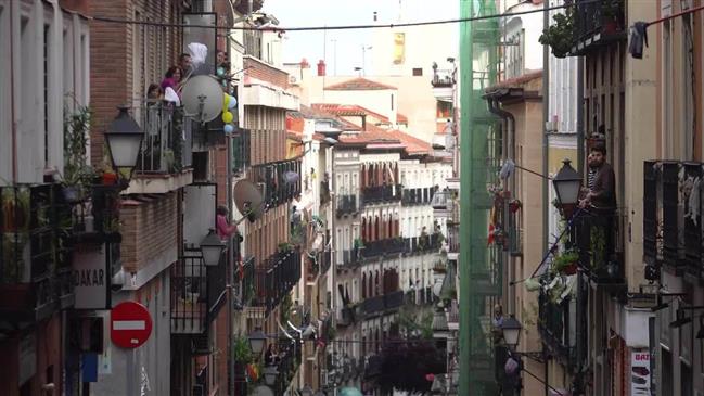 Madrid neighbors greet each other with mops during COVID-19 lockdown